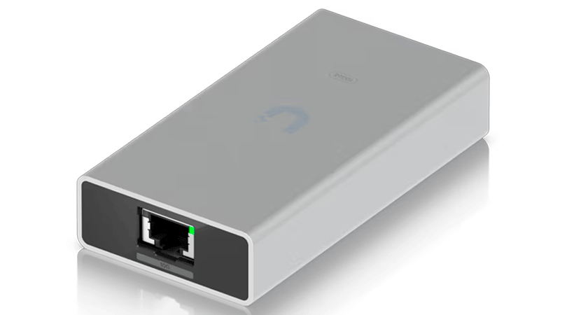 Адаптер Ubiquiti 10G Ethernet крупным планом — виден порт RJ45 с зелёным индикатором активности, корпус из алюминиевого сплава и логотип на верхней панели