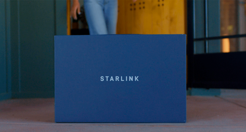 Синяя коробка с логотипом Starlink, стоящая на полу у входа в здание.
