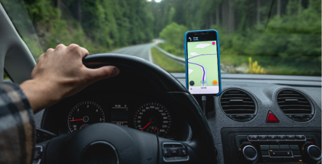 Навигация в автомобиле: водитель держит руль, на смартфоне включена карта маршрута, а значит есть доступ к интернету